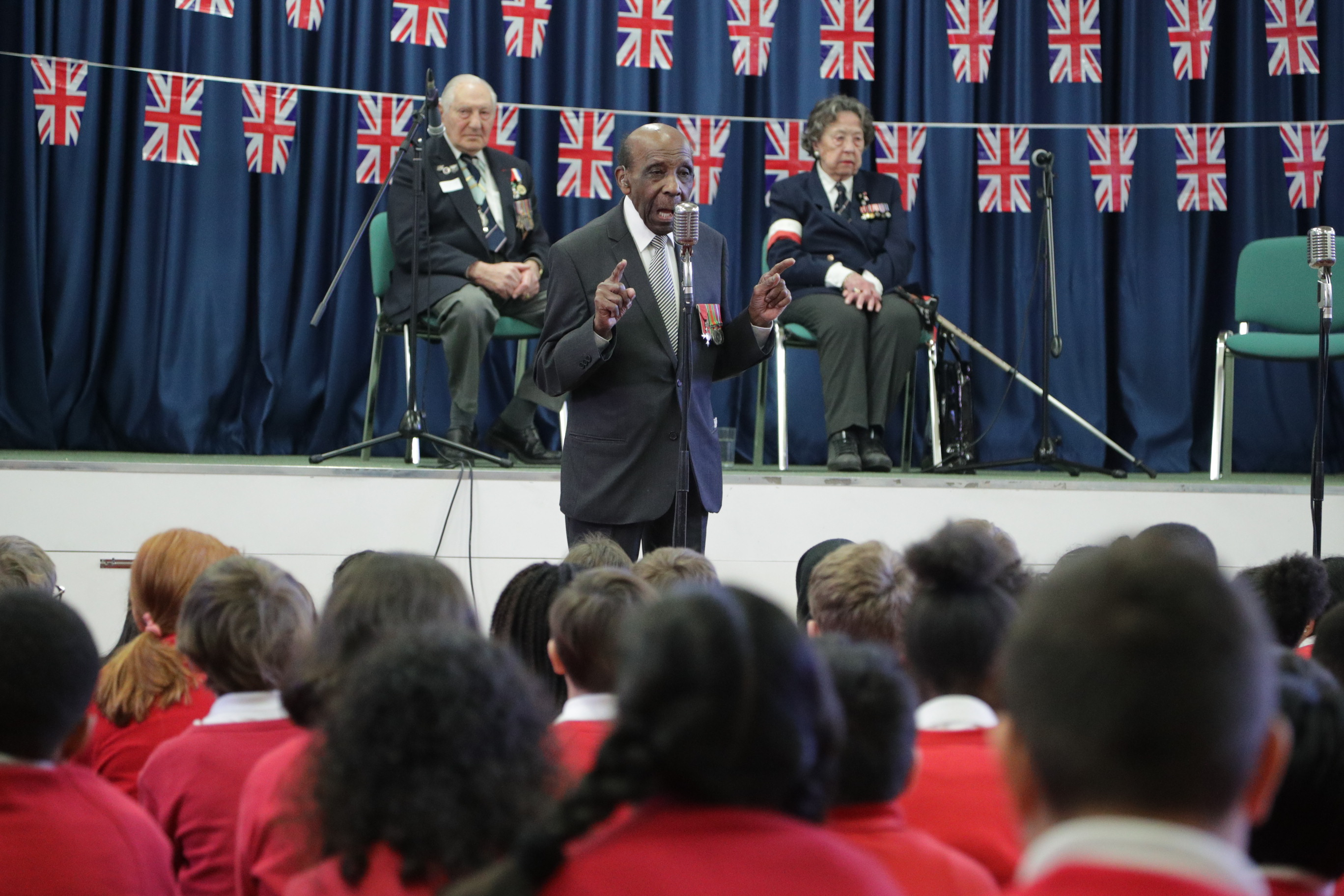 Veteran talking to group of children in assembly