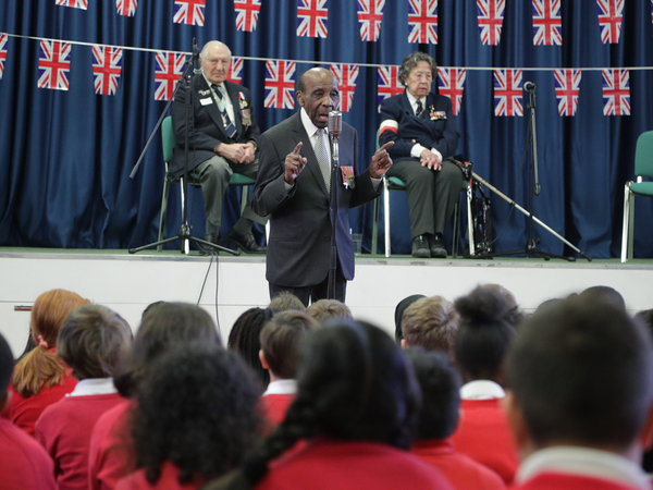 Veteran talking to group of children in assembly