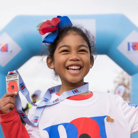 Little girl cheering with her medal at Poppy Run finish line