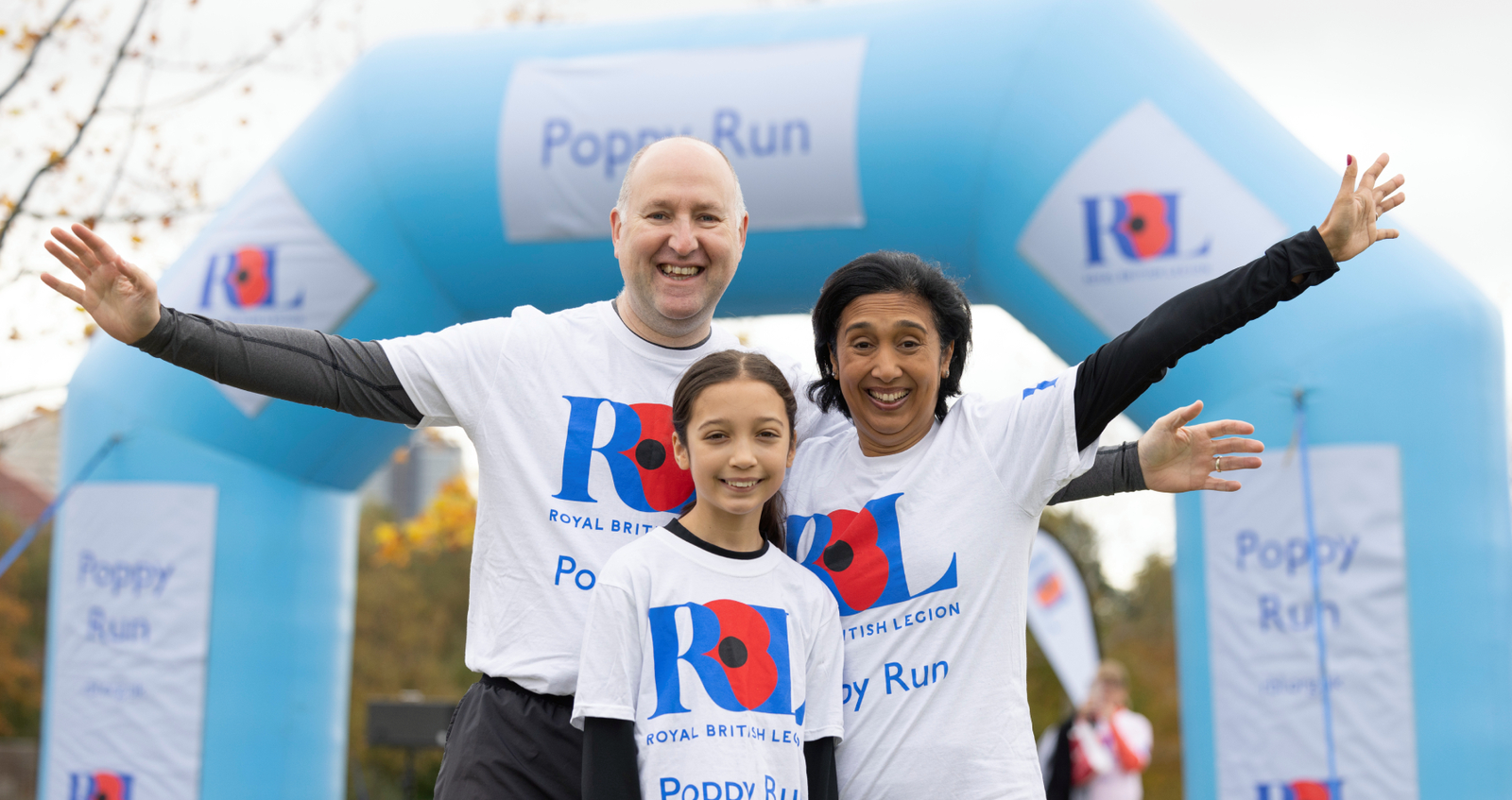 Family of three (father, mother and daughter) cheering at the Poppy Run entrance