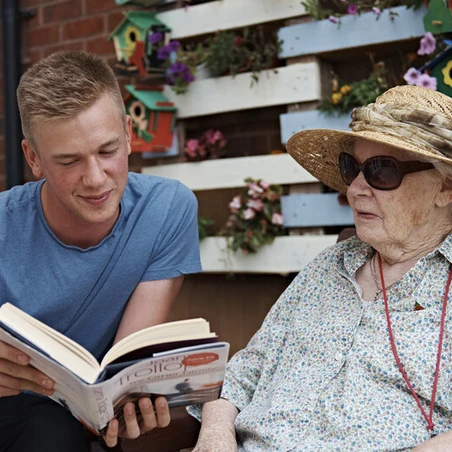 A young volunteer reading to a member of the Armed Forces community
